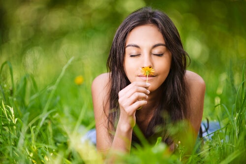 Frau riecht an einer Blume mit einem glücklichen Gesicht