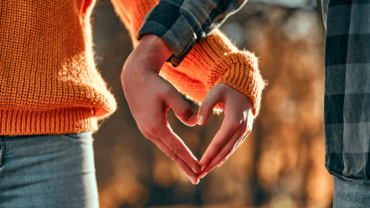 Die Hände des Paares bilden ein Herz, das die Bedeutung der Sätze zum Verlieben symbolisiert